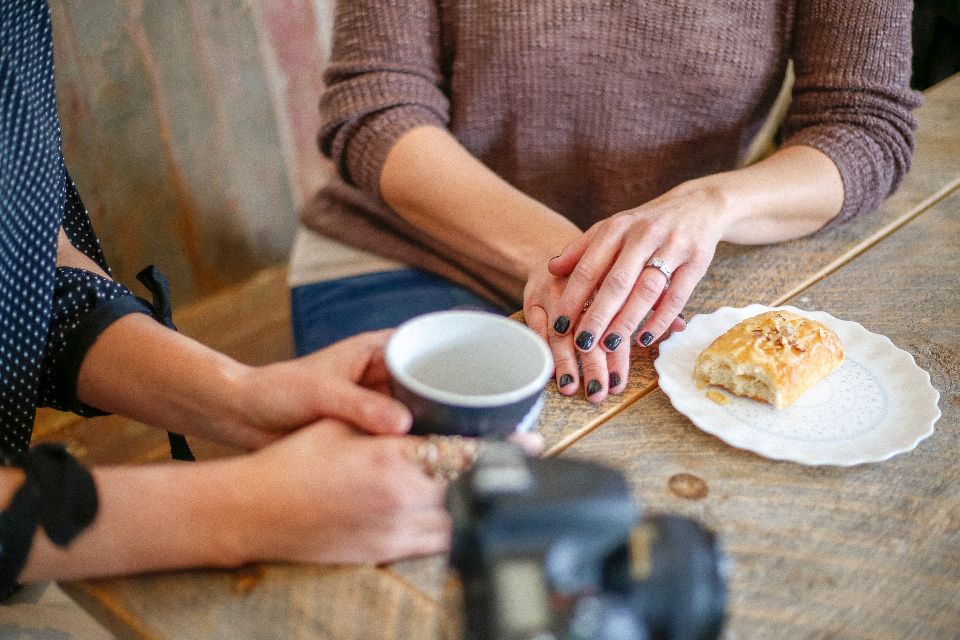 Two people talking over coffee at a wooden table